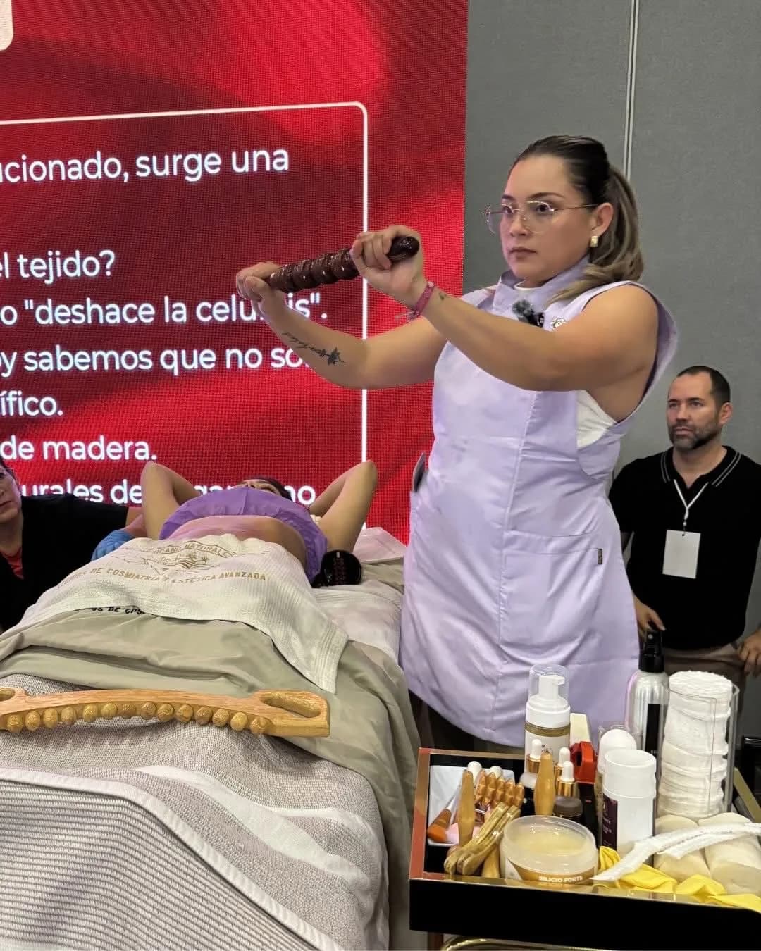 Ponente demostrando una técnica de masaje con rodillo de madera ante el público del Showroom Académico